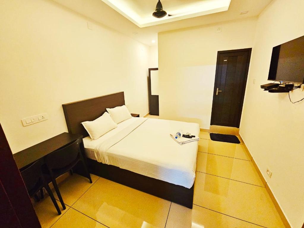 ein Hotelzimmer mit einem Bett und einem TV in der Unterkunft Apsara Residency in Perintalmanna