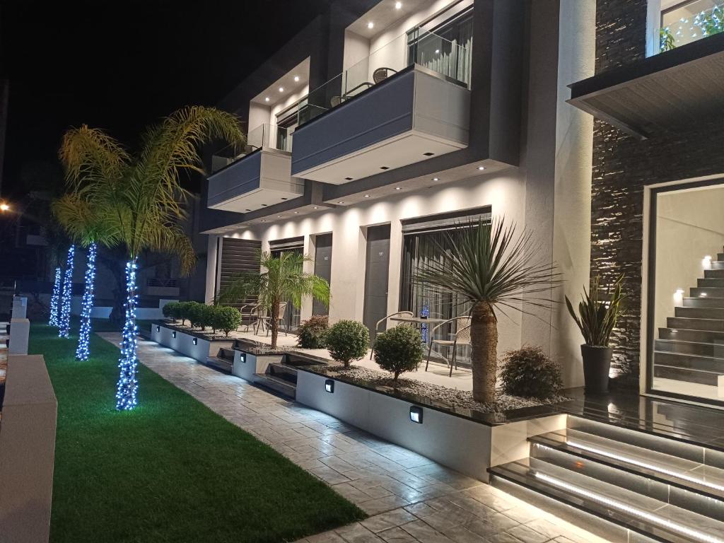 a house with palm trees and lights in the yard at Oikos 9 Rooms and Suites in Nafpaktos