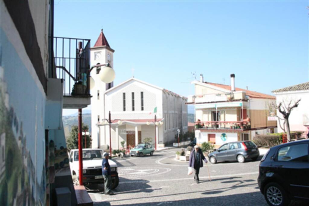 Uma mulher a descer uma rua da cidade com uma torre de relógio em Casa Isabella Napoli em Montegiordano