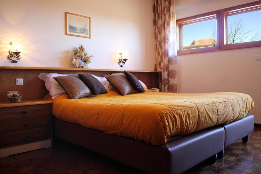 1 dormitorio con 1 cama con sábanas y almohadas de color naranja en Hotel Tre Cime Terminillo en Terminillo