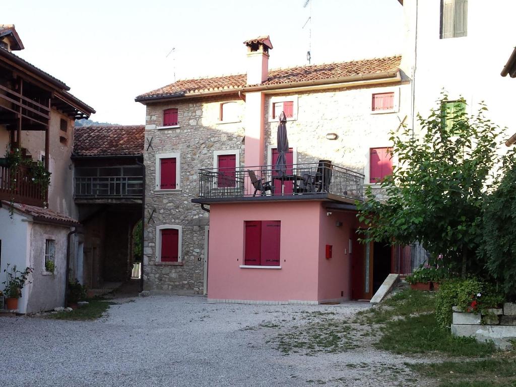 un edificio rosa con puertas rojas en un patio en Casa Del Nonno, en Tarzo