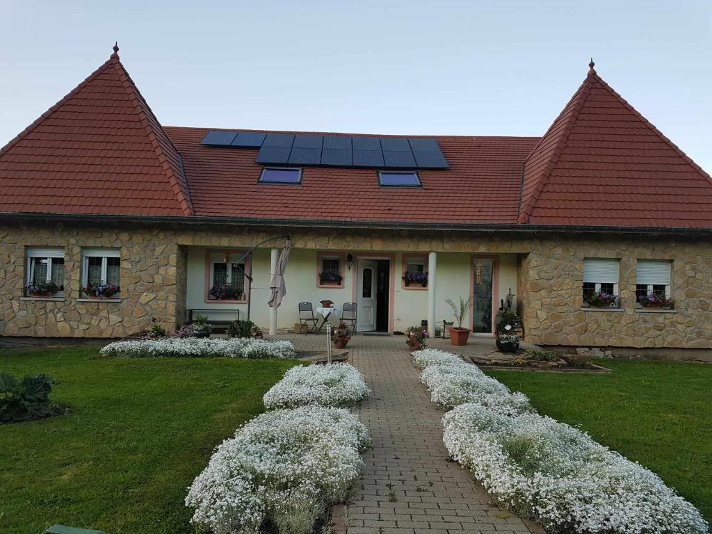 une maison avec une rangée de fleurs blanches devant elle dans l'établissement Appartement à l étage d une maison en pleine campagne, à Métairies-Saint-Quirin