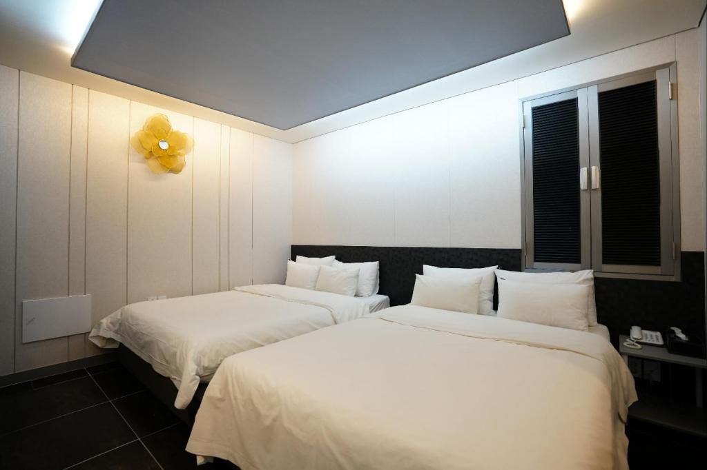 two beds in a room with white sheets and a yellow balloon at Shinchon Y Hotel in Seoul