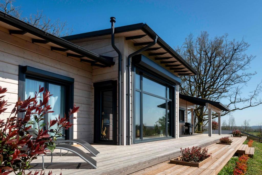 Cette maison dispose de grandes fenêtres et d'une terrasse en bois. dans l'établissement Un petit îlot de confort - made in Finland, à Monflanquin