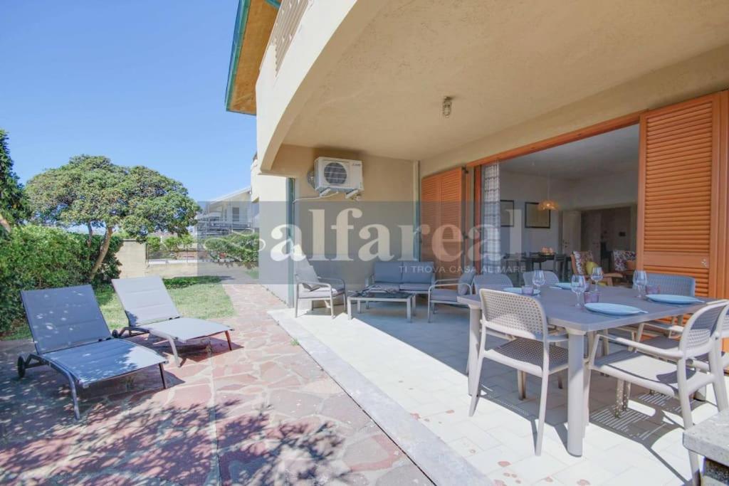 une table et des chaises sur le patio d'une maison dans l'établissement Villetta Marco Polo, 3 camere, clima, giardino e posto auto, a soli 50 m dal mare! by Alfareal, à Castiglione della Pescaia