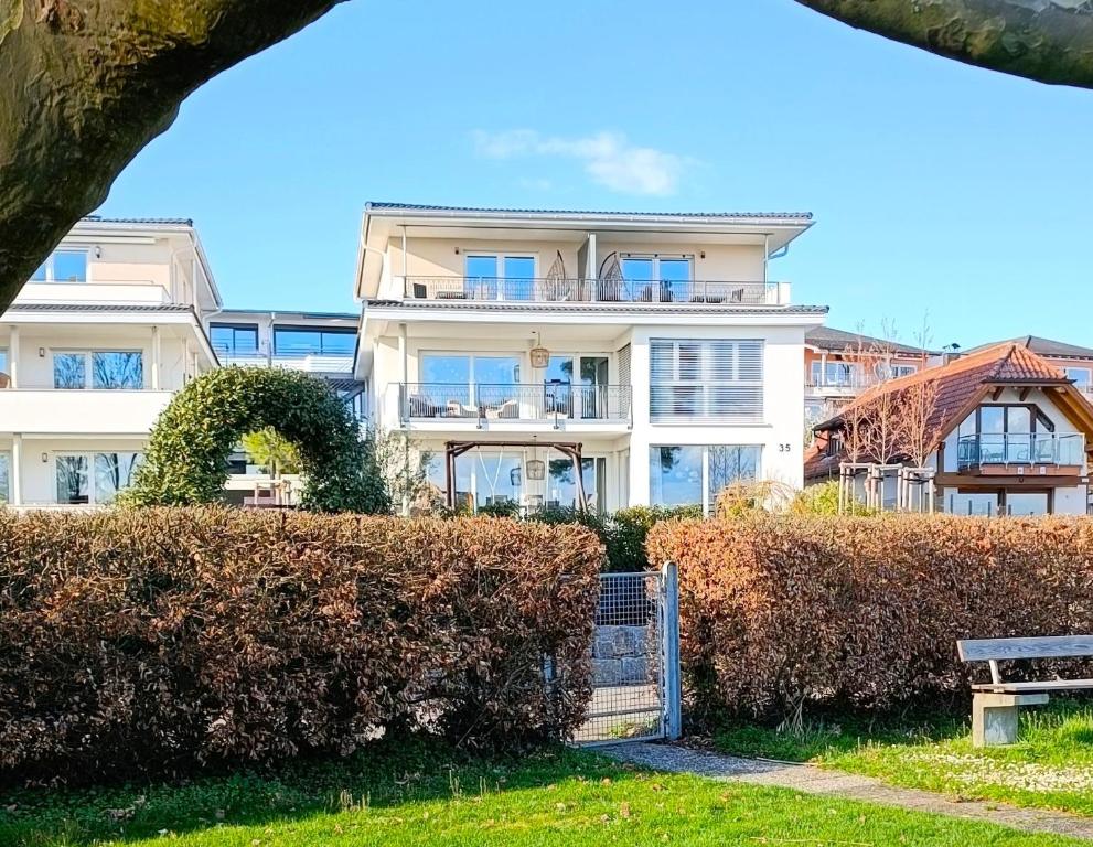 a white building with a hedge in front of it at MAISON AMAND - Am See mit Privatstrand in Immenstaad am Bodensee