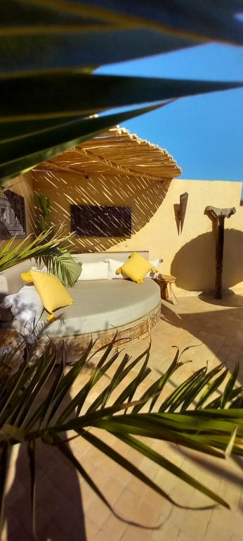 1 cama con almohadas amarillas y sombrilla en Riad Miss Caracal, en Marrakech