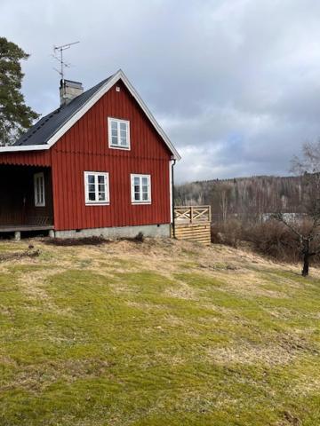 um celeiro vermelho sentado em cima de um campo de relva em Åsen em Arjäng