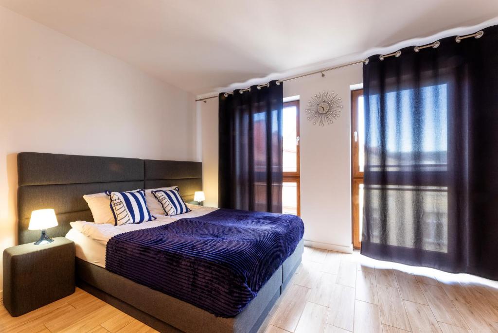 een slaapkamer met een bed en een groot raam bij Apartamenty Bałtyckie - Grand Baltic - WIFI, Klimatyzacja, Sala Zabaw, Taras wypoczynkowy, centrum Ustki in Ustka