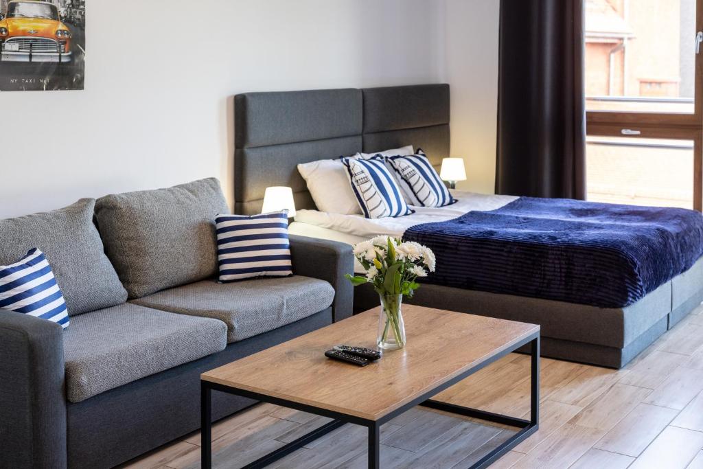 a living room with a couch and a bed at Apartamenty Bałtyckie - Grand Baltic - WIFI, Klimatyzacja, Sala Zabaw, Taras wypoczynkowy, centrum Ustki in Ustka