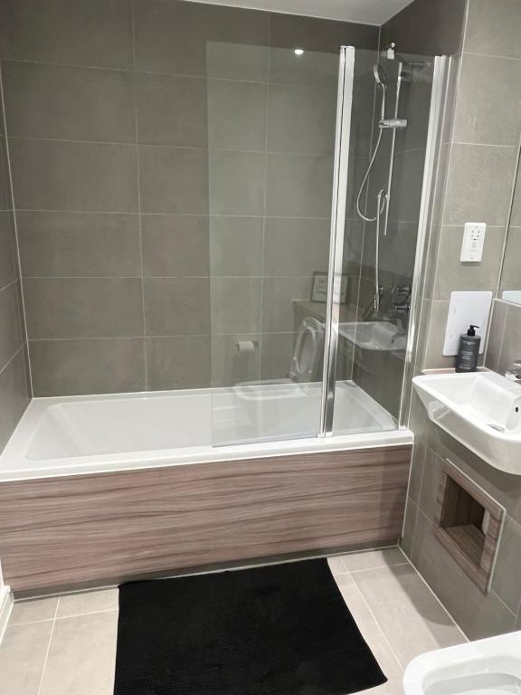 a bathroom with a shower and a tub and a sink at Lovely Private double room in Barking
