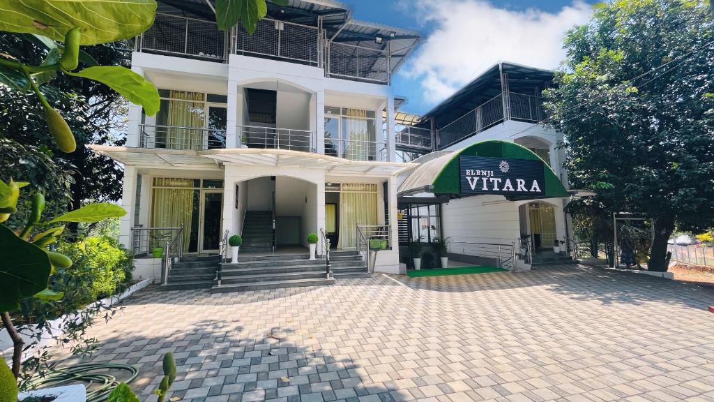 un edificio blanco con un cartel que lee Villa en Elenji Vitara Resort Munnar en Munnar