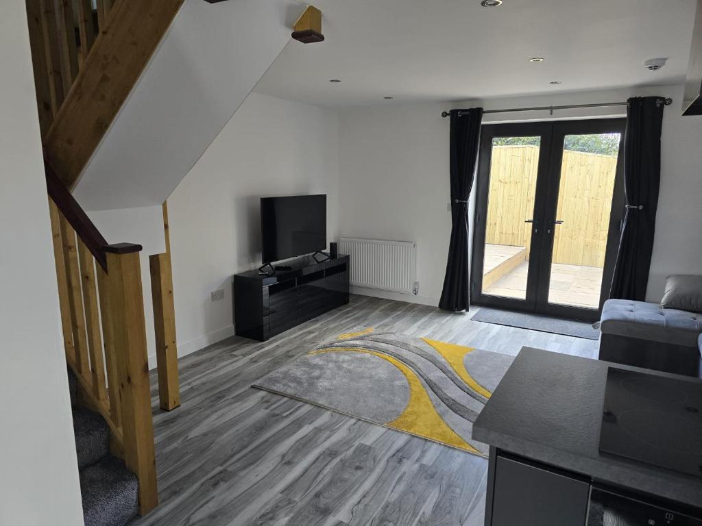 een woonkamer met een bank en een televisie bij Ole Butt Cottage in Cinderford