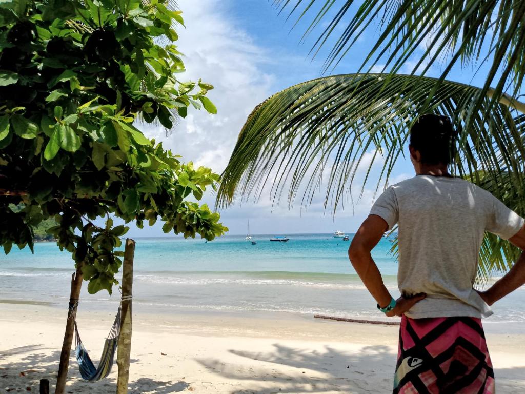 a man standing on a beach looking at the ocean at Barook Chalet in Mersing