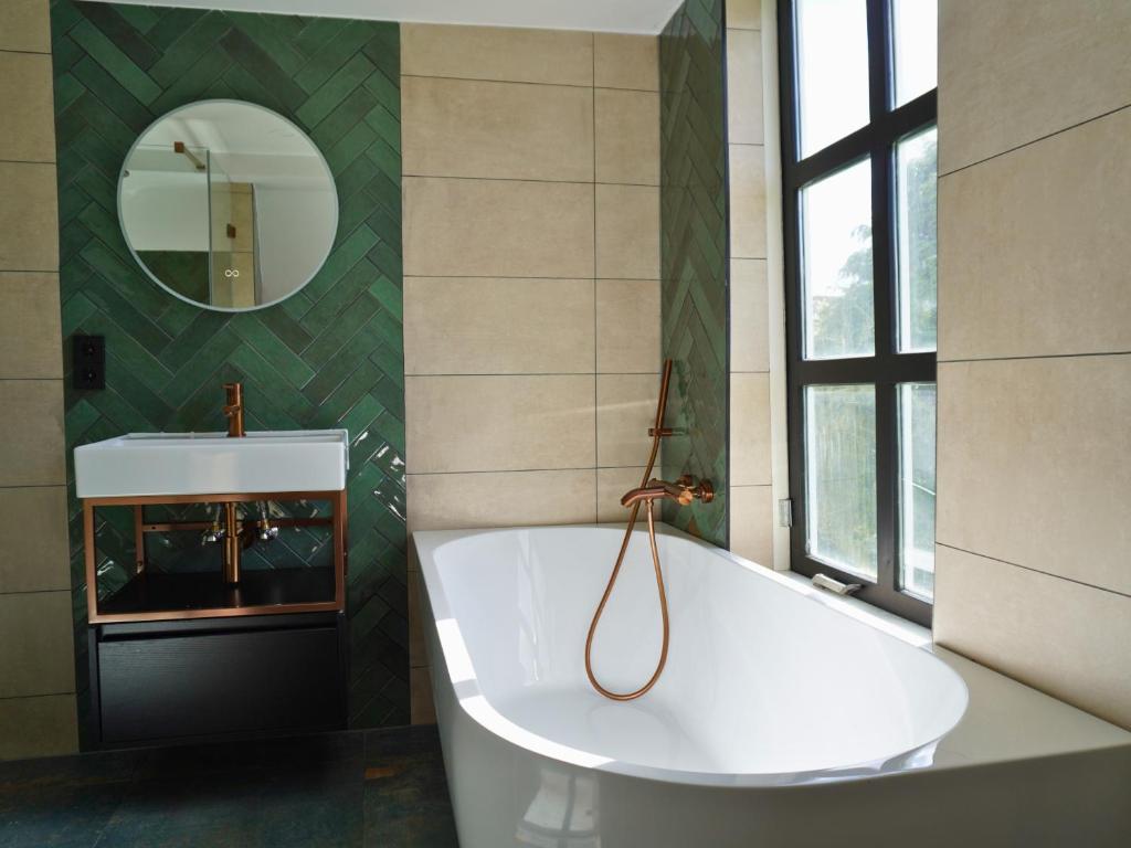 a white tub in a bathroom with a mirror at B&B Catharinenburg in Melissant