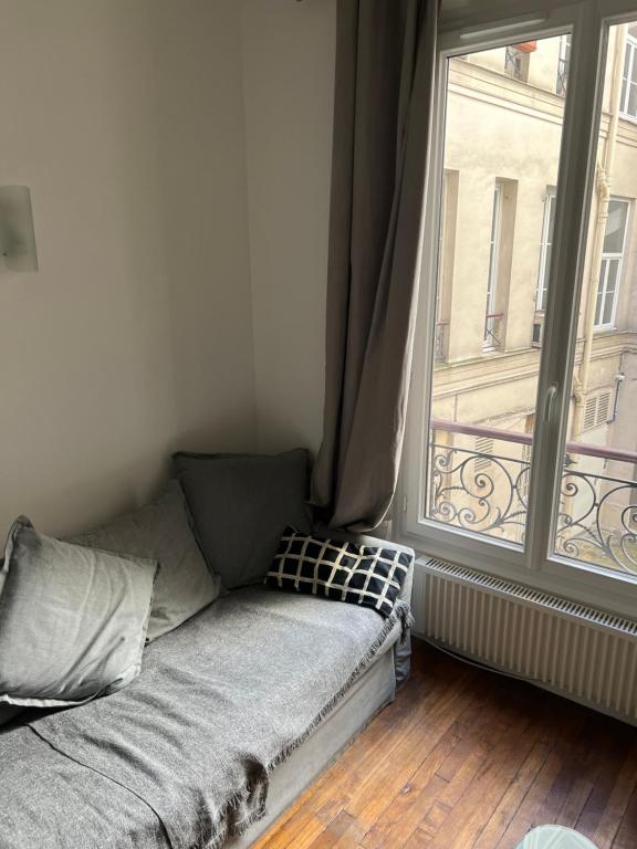 - un canapé dans une chambre avec une grande fenêtre dans l'établissement Paris - Champs Élysées - Arc de Triomphe, à Paris