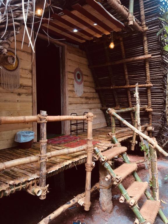 Cabaña de madera con cama delante en Bamboohutz, en Auroville