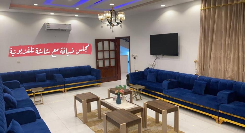 ein Wohnzimmer mit blauen Sofas und einem TV in der Unterkunft شاليهات ميدنايت in Rabigh