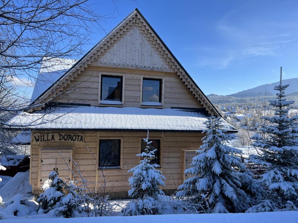 a small cabin with a sign on it in the snow at Villa Dorota in Zakopane