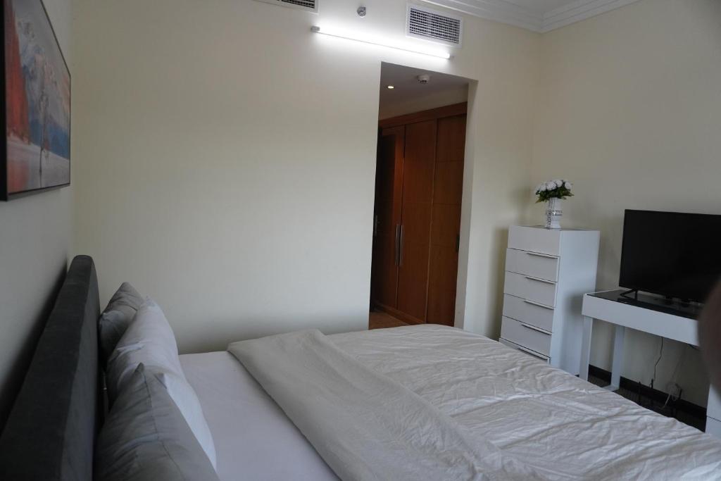 a white bedroom with a bed and a television at Peace House-private room with bathroom for 2 guest in Dubai