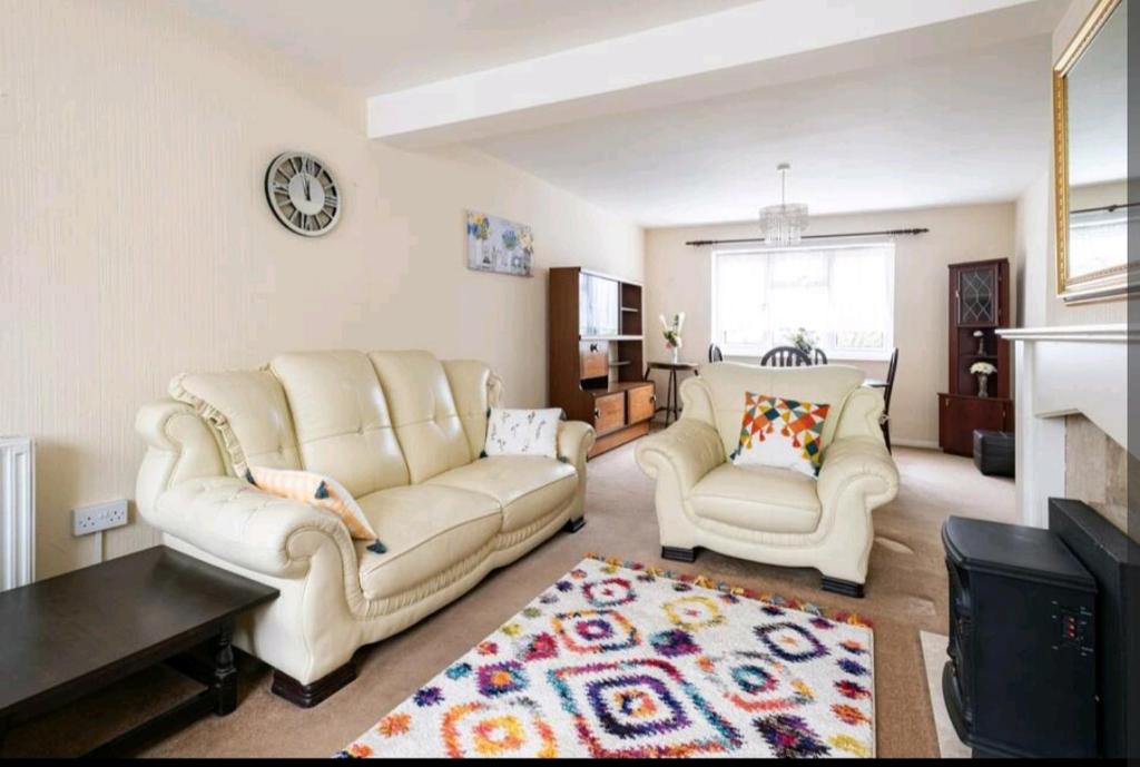 a living room with two white couches and a fireplace at London Stratford Holiday Home in London