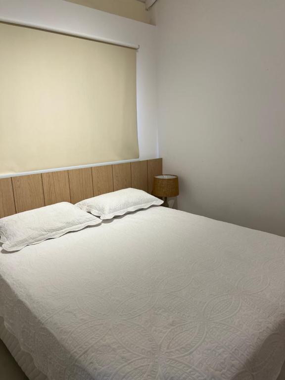 1 dormitorio con 1 cama grande con sábanas blancas en Vila do Lago Praia do Forte en Mata de Sao Joao