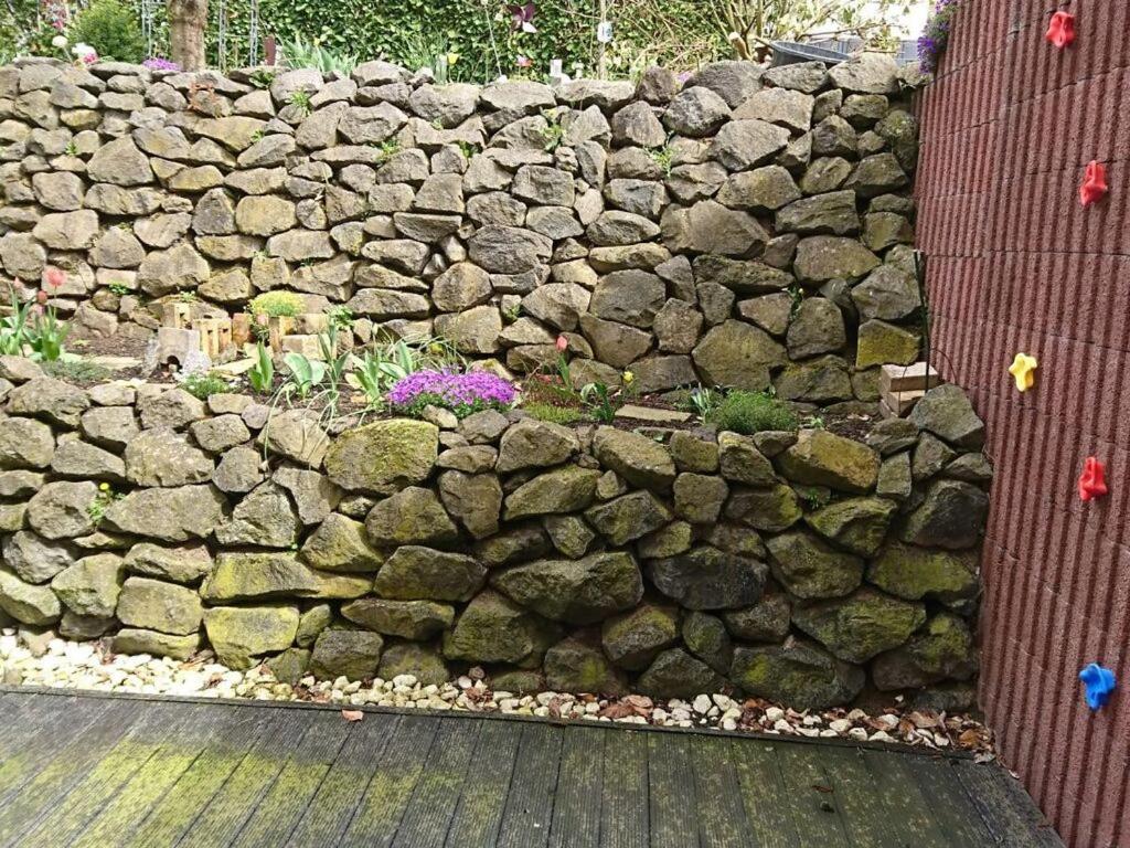 a stone wall with some flowers in front of it at Rednak Modern Retreat in Polch