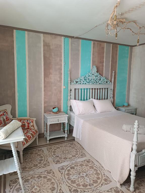 a bedroom with a white bed and a chair at Avó da Rosa 1 in Ribeira Quente
