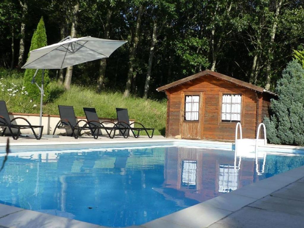 una piscina con sillas, una sombrilla y una casa en Attractive holiday home with garden, en Saint-Marcet