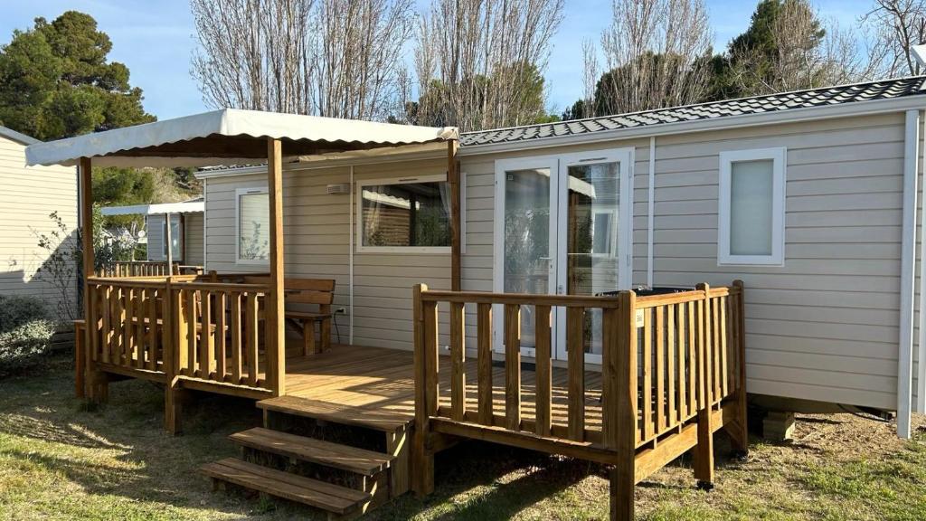 a cabin with a wooden deck with a gazebo at Mobil-home - Narbonne-Plage - Clim, TV in Narbonne-Plage