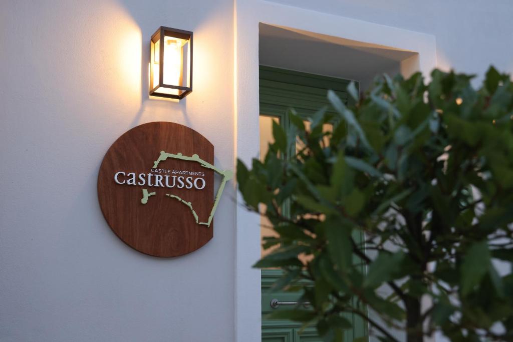 a sign on the side of a wall with a plant at Castrusso Castle apartments in Chios