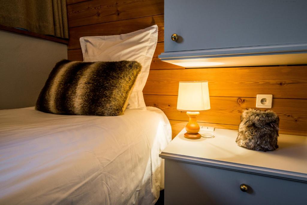 a bedroom with a bed and a lamp on a night stand at Hotel Le Samoyede in Morzine