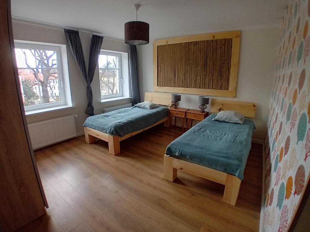 a room with two beds and two windows at W parku przy teatrze in Szczawno-Zdrój
