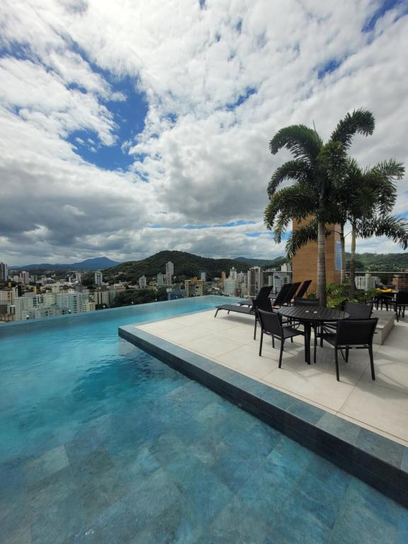 a swimming pool with a table and chairs on a building at Cosmopolitan 2007 - Apto 800m da Vila Germânica in Blumenau