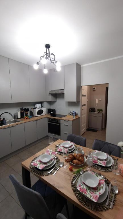 una cocina con una mesa de madera con platos. en Underground Cave Apartment en Wieliczka