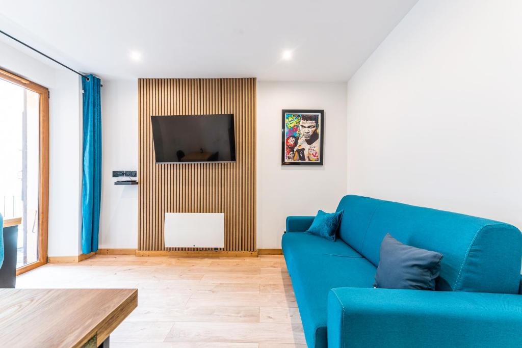 a living room with a blue couch and a tv at Studio The Greatest in Moutiers