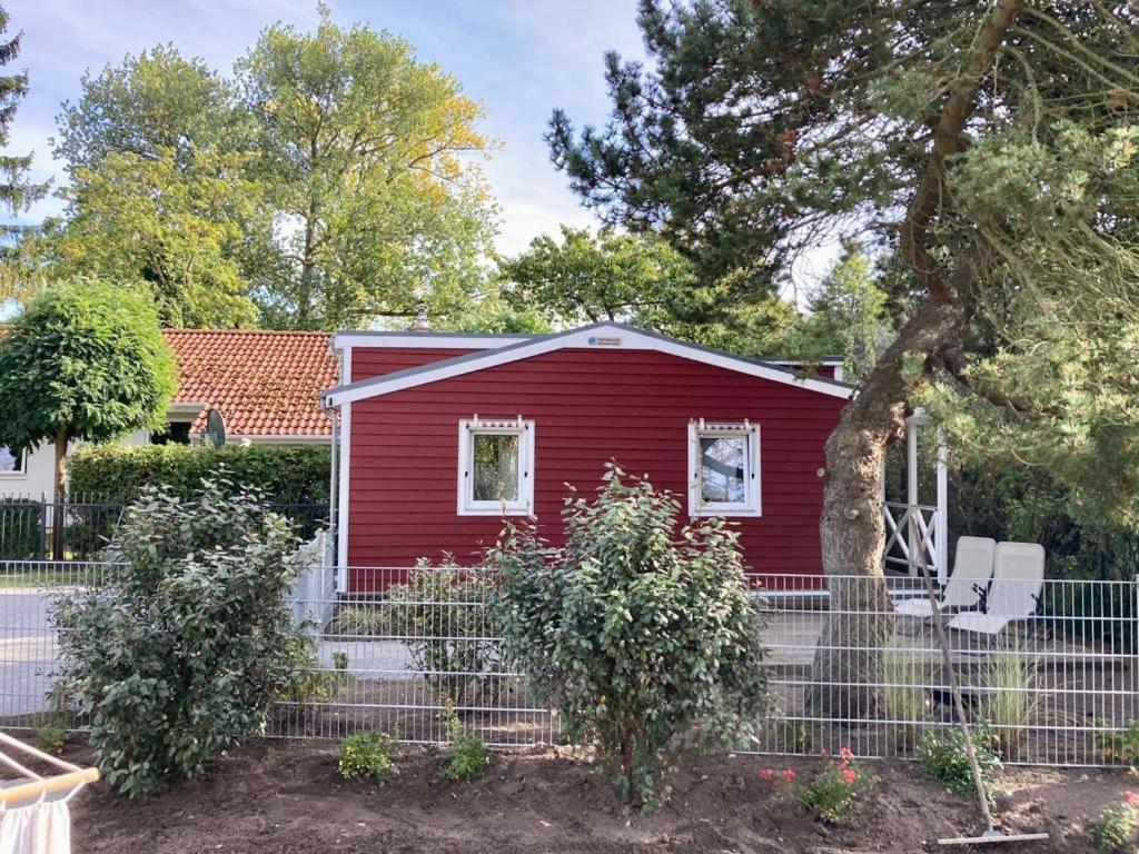 czerwony dom z płotem przed nim w obiekcie Tiny House am Meer w mieście Heringsdorf