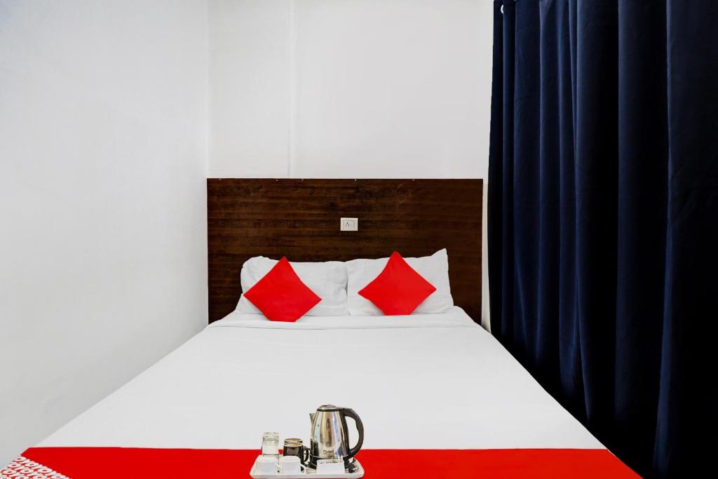 um quarto com uma cama branca e almofadas vermelhas em Flagship Pride Inn em Bangalore