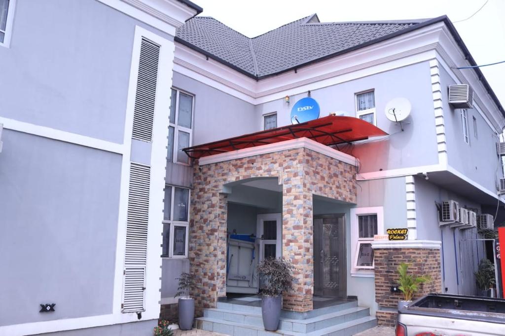 une maison blanche avec un toit rouge dans l'établissement Rocket Room Hotel & Suites Limited, à Port Harcourt