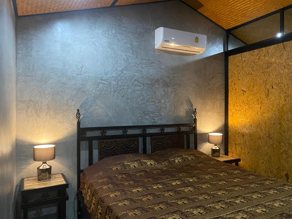 a bedroom with a bed and two night stands with lamps at แครินโฮมสเตร์ in Koh Lone