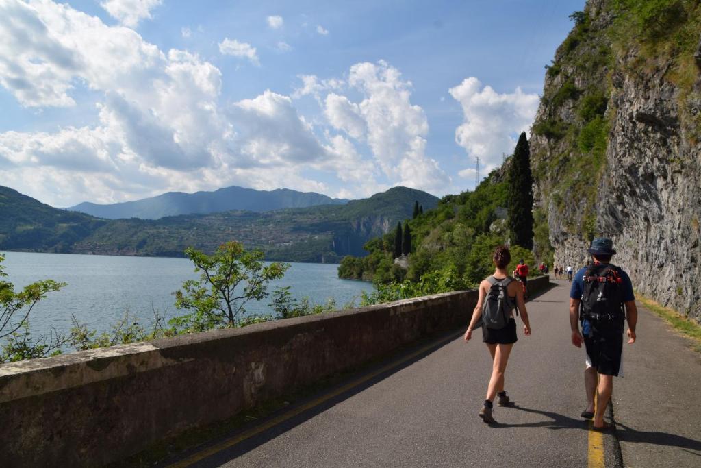 Angelo&Marì Mountain Lake Iseo Hospitality في مارون: شخصان يسيران على طريق بجوار بحيرة