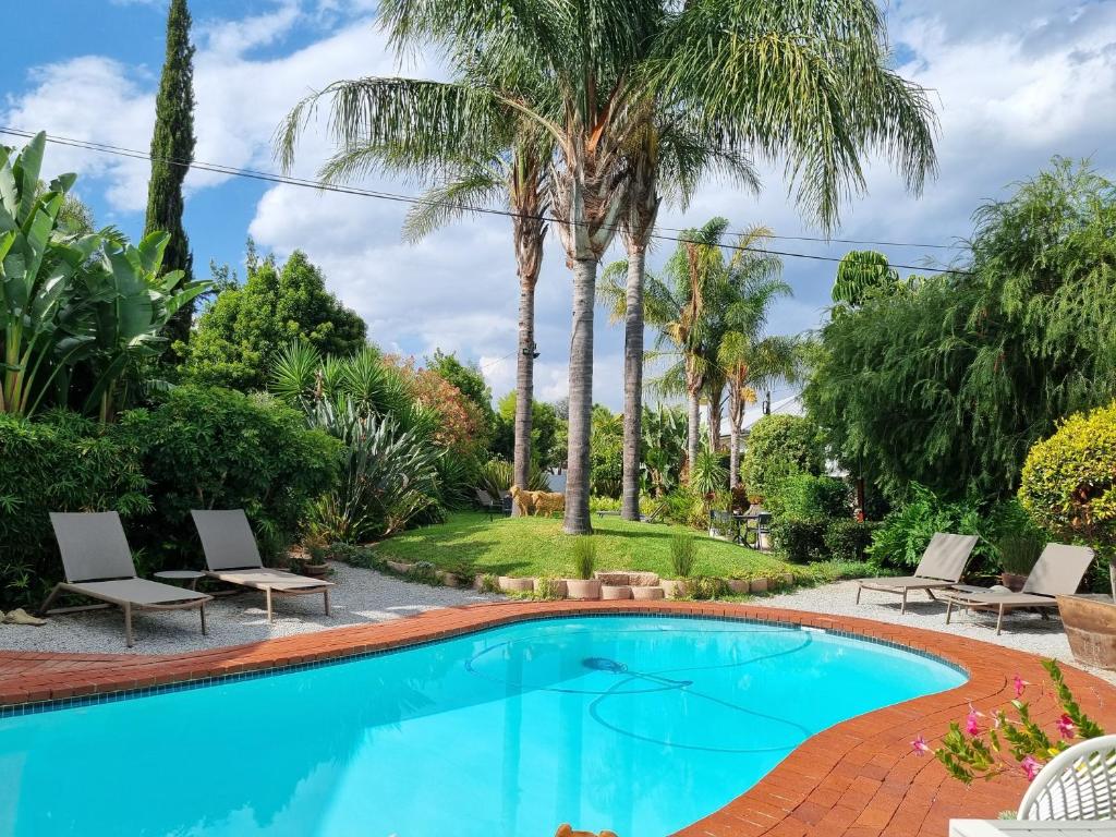 a swimming pool in a yard with palm trees at Ballinderry, The Robertson Guest House in Robertson