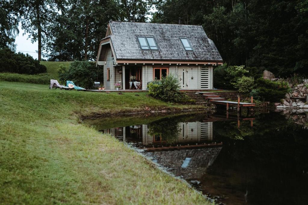 una casa con un estanque delante de ella en Hortus Paradisum en Ikšķile