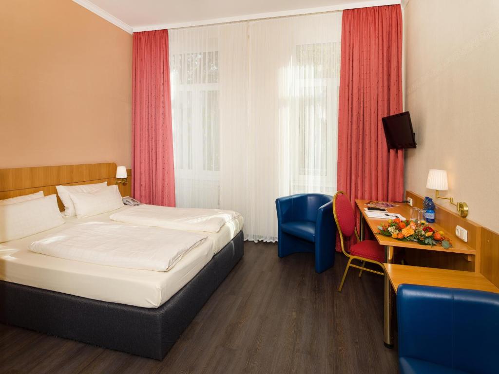 マインツにあるホテル ケーニヒスホフのベッドとデスクが備わるホテルルームです。
