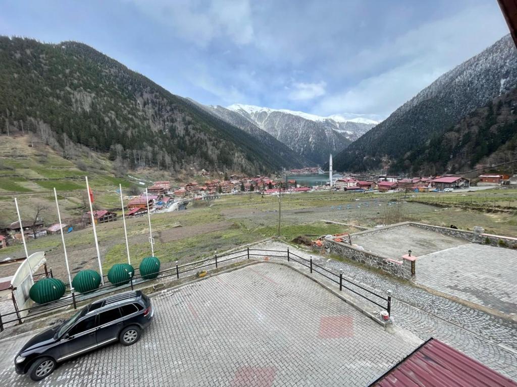 a car parked in a parking lot with mountains in the background at Uzungöl Bikka Pansiyon in Uzungöl