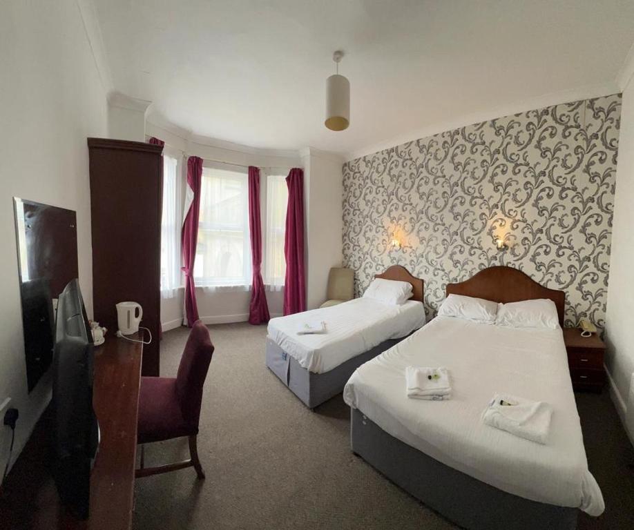 a hotel room with two beds and a tv at The Embassy Hotel in Great Yarmouth