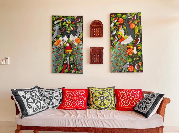 three paintings on a wall above a couch at Best View Malindi Guest House in Mwembe Maepe