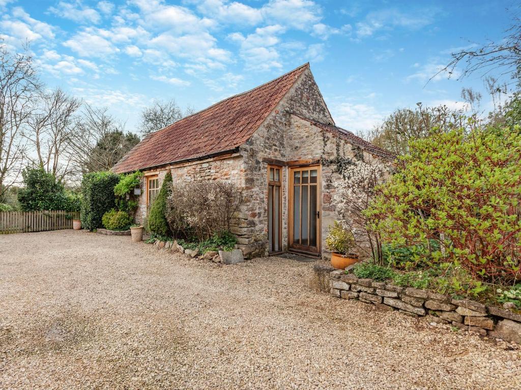 a small stone house with a roof at Midsummer Cottage Retreat in Pilton