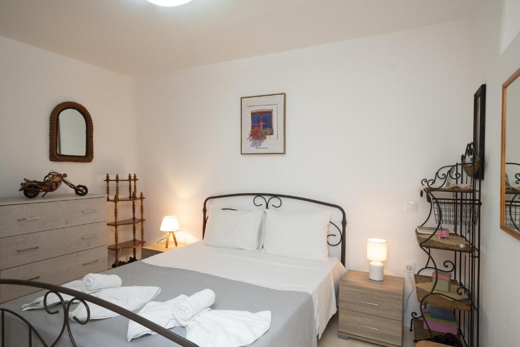 um quarto com uma cama com lençóis brancos e almofadas brancas em Spilia Apartments & Suites Mykonos em Agrari
