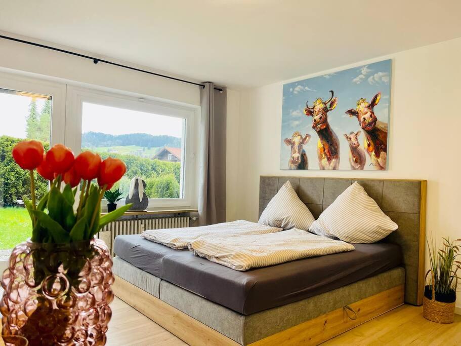 a bedroom with a bed with a vase with red flowers at BERGflair inkl. Oberstaufen PLUS in Oberstaufen